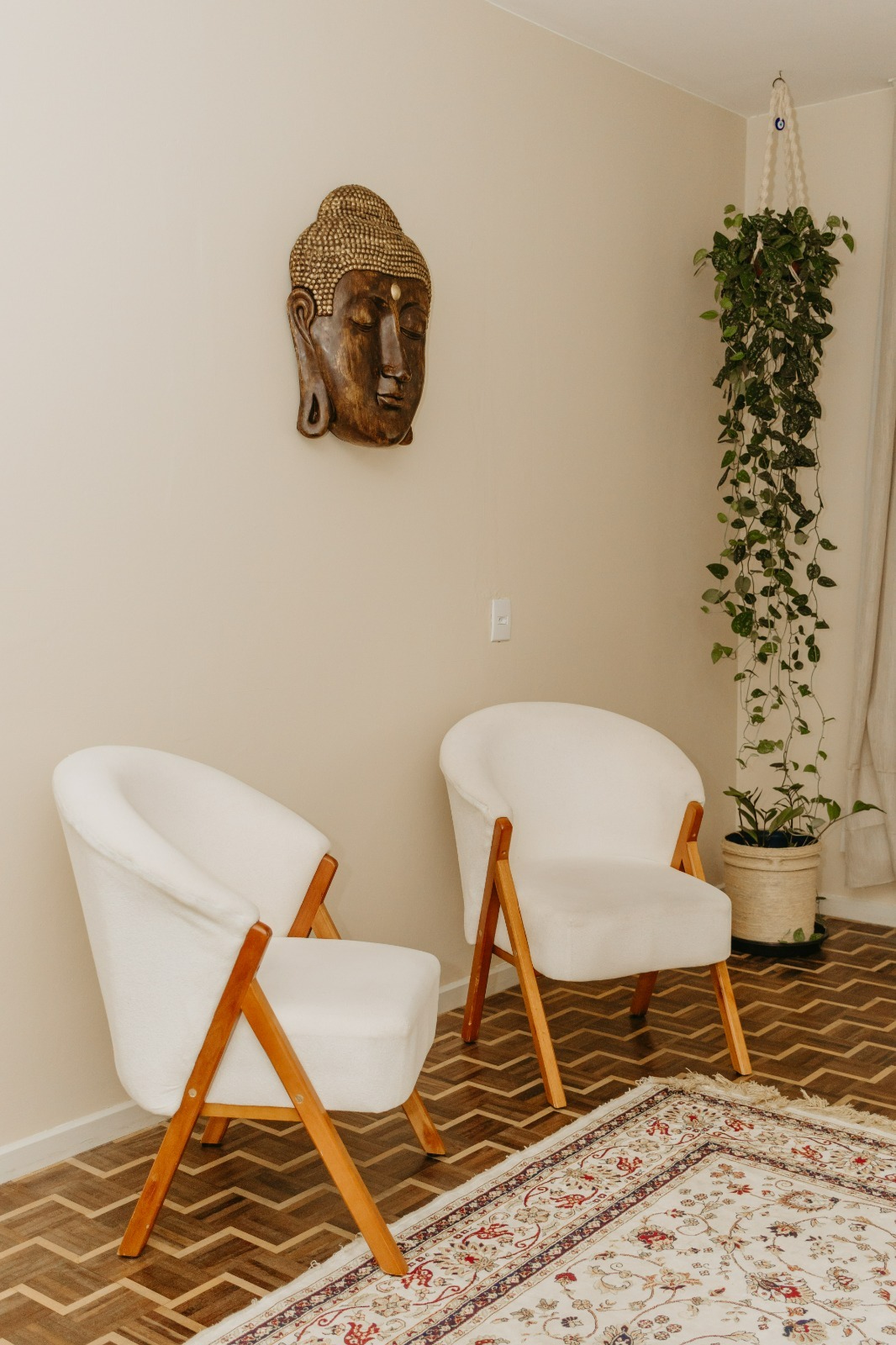 Sala de terapia com poltronas brancas, Buda esculpido e planta pendente, Espaço Shanti